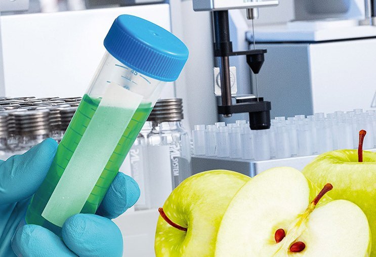 Gloved hand holding a sample vial near sliced apples in a lab, illustrating PAL Solutions workflow solutions support