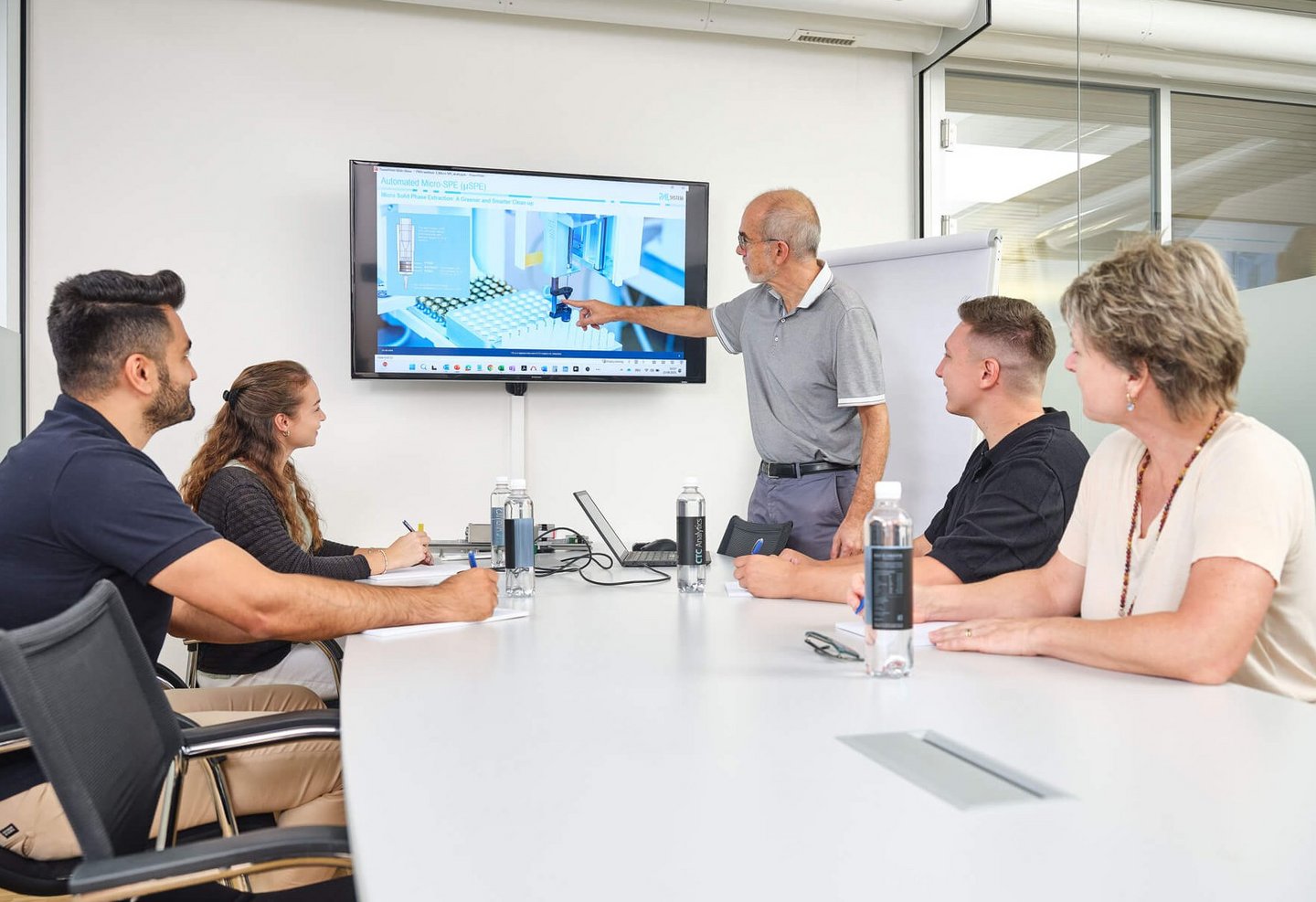 A Team in a meeting room watching a presenter explain a technical diagram on screen during a PAL Solutions Training